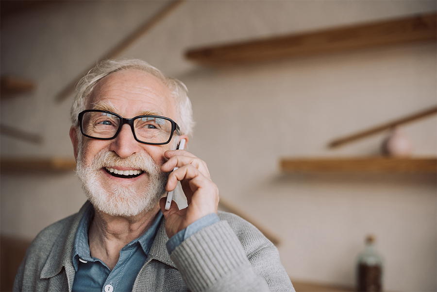 uomo anziano sorride al telefono